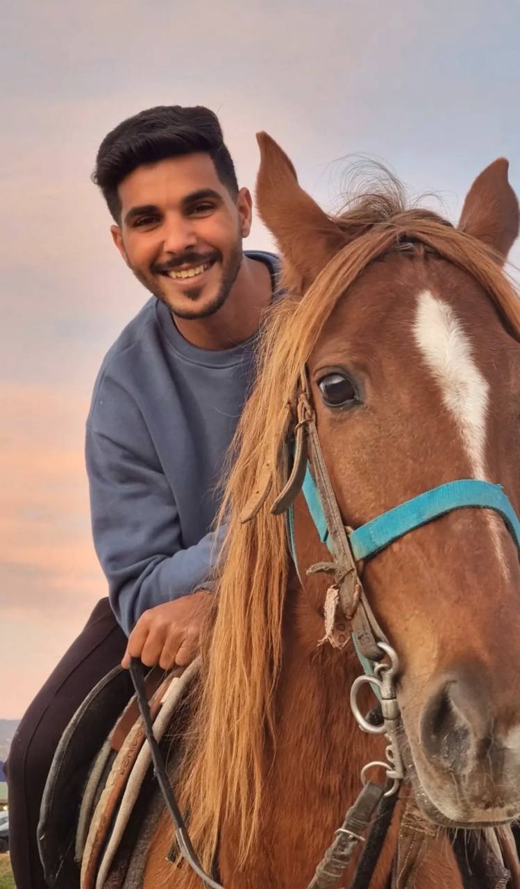 Cavalier souriant auprès d’un cheval brun