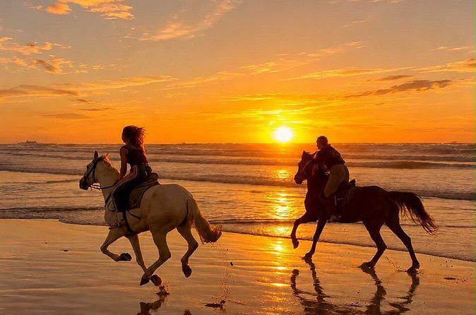 Deux cavaliers galopant sur la plage au coucher du soleil