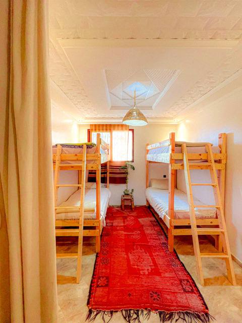 Dortoir avec lits superposés et tapis rouge traditionnel