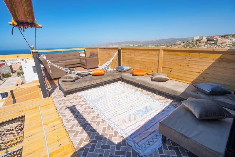 Terrasse de l’hostel avec salons, hamac et vue sur l’océan